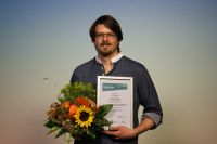 Photo of the winner of the FAIRest Dataset Award 2024 with flowers and certificate